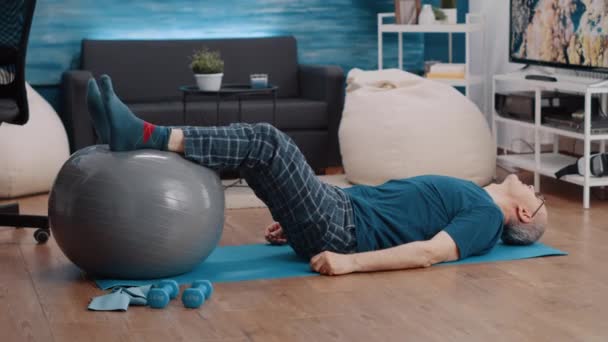 Gepensioneerde met behulp van fitness toning bal en tillen benen — Stockvideo