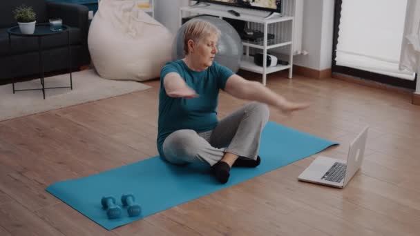 Starý člověk se dívá na video s lekcí cvičení na notebooku — Stock video