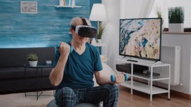 Emekli, dambıllarla fiziksel egzersiz yapmak için vr gözlük kullanıyor.