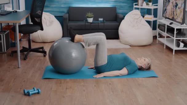Женщина использует мячик для тренировки мышц ног на коврике — стоковое видео