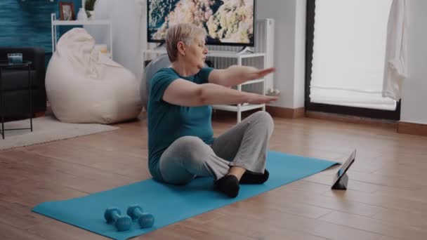 Mujer mayor siguiendo el programa de lección de entrenamiento en la tableta — Vídeos de Stock