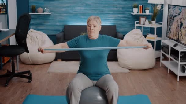 Elder adult sitting on yoga mat and pulling resistance band Stock