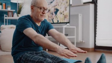 Yaşlı bir adamın yoga minderinde gerinme egzersizi yaptığı yakın plan.