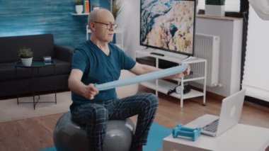 Emekli asker, silah kaslarını çalıştırmak için direniş bandını esnetiyor