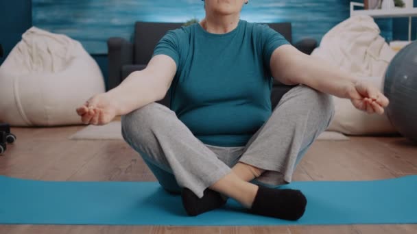 Verouderde vrouw doet meditatie zittend in lotuspositie — Stockvideo