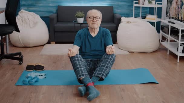 Aged man doing meditation while sitting in lotus position — Stock Video