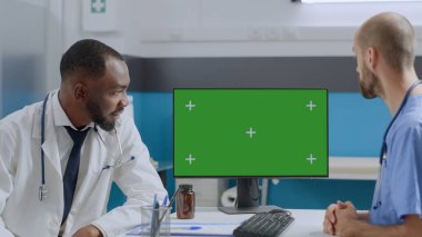 Çok ırklı ekip yeşil ekran kroma anahtar bilgisayarı ile izole edilmiş ekrana bakıyor.