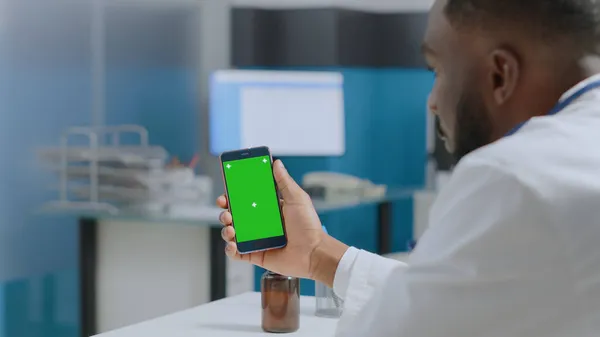 Médecin thérapeute afro-américain tenant un téléphone à clé chromatique à écran vert avec affichage isolé — Photo