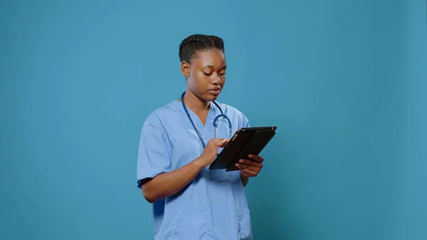 Afrykańska pielęgniarka w mundurze za pomocą tabletu cyfrowego — Zdjęcie stockowe