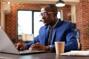 Ofis işinde proje ve strateji planlamak için dizüstü bilgisayarda çalışan bir iş adamı