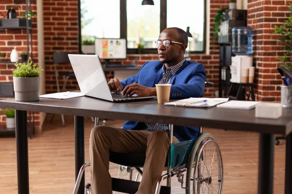 Business man sitting in wheelchair working on laptop to plan project and strategy in office — Stock Photo, Image