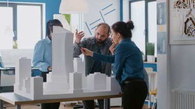 İş arkadaşları bina modelini analiz ediyor, mimari tasarım üzerine takım çalışması yapıyor.
