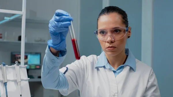Médico de microbiología sosteniendo tubo de ensayo lleno de sangre —  Fotos de Stock
