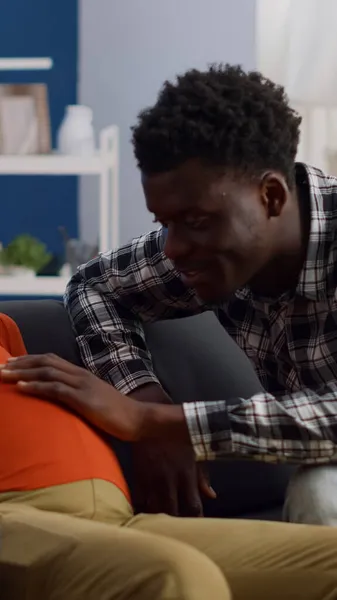 Oturma odasındaki kanepede oturan ırklar arası hamile bir çift. — Stok fotoğraf