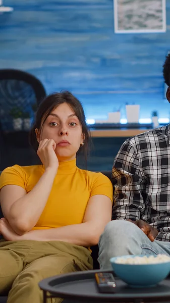 Young interracial couple watching television eating popcorn — Stock Photo, Image