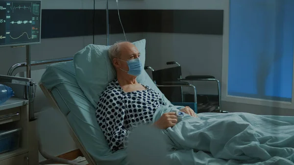 头戴口罩坐在病房病床上的病人 — 图库照片