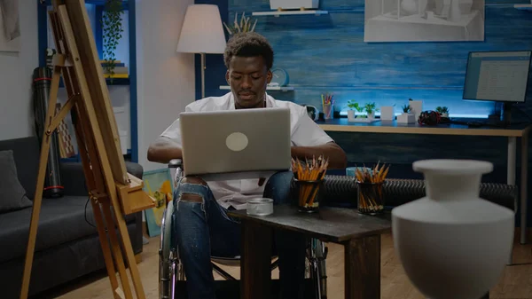 車椅子の黒人がノートパソコンで絵を描く — ストック写真