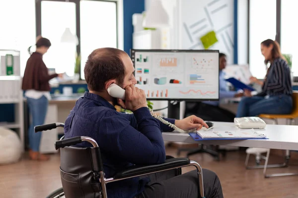 Paralyzed disabled businessman talking at landline discussing marketing strategy — Stock Photo, Image