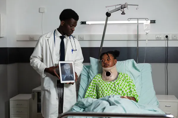 Afro-Amerikan radyoloji uzmanı elinde tabletle kemik radyografisini tartışıyor. — Stok fotoğraf