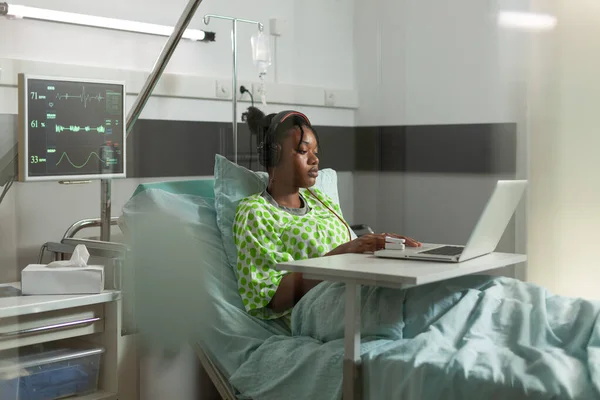 Afroamerykanin chory pacjent stojący w łóżku podczas wizyty lekarskiej oglądanie filmów online — Zdjęcie stockowe