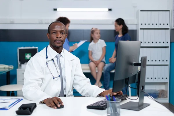 Ritratto di medico afro-americano seduto alla scrivania nell'ufficio ospedaliero — Foto Stock