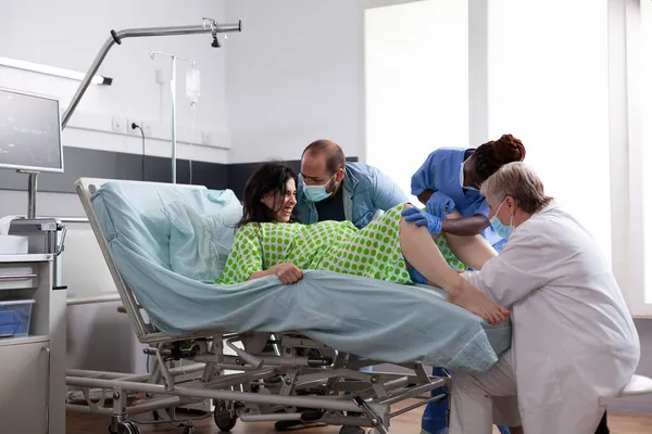 Multi equipe médica étnica ajudando com o parto infantil — Fotografia de Stock