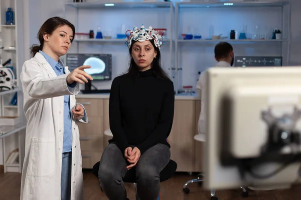 Médico neurólogo mostrando monitor con actividad cerebral a paciente con eeg scanner — Foto de Stock