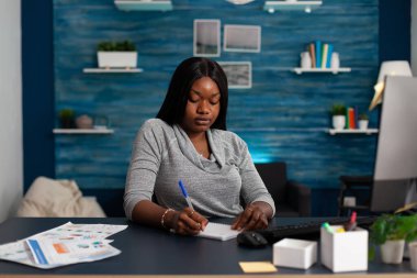 Afrika kökenli Amerikalı kadın ders kitabı kağıdına not alıyor