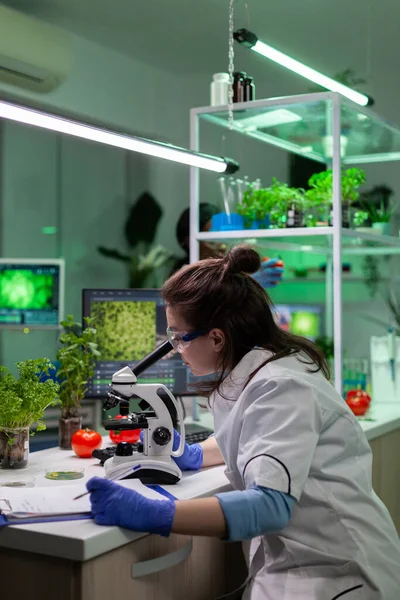 Biólogo investigador médico analizando muestras de plantas gmo utilizando microscopio médico —  Fotos de Stock