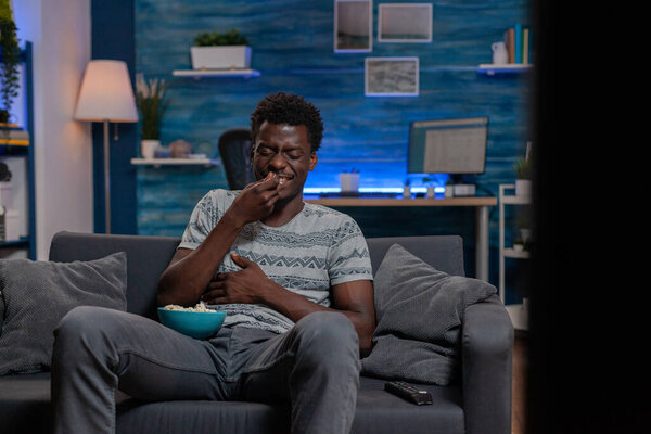 African american guy watching entertainment movie on television laughing
