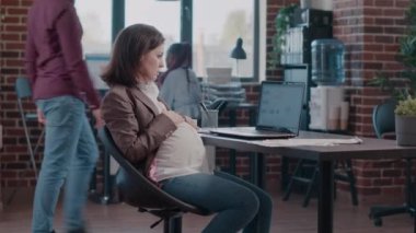 Hamile kadın iş projesinde çalışmak için dizüstü bilgisayar kullanıyor.