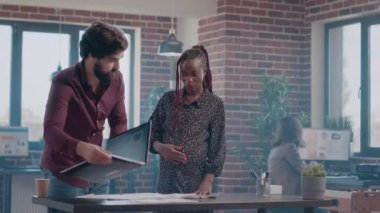 Masadaki iş belgelerini inceleyen hamile kişi ve adam.