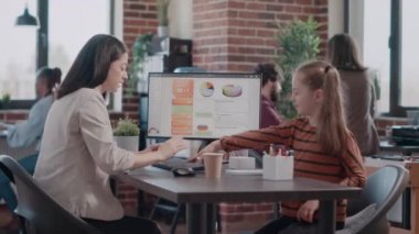 Küçük kız çok ırklı iş adamlarını oyalarken anne bilgisayar kullanıyor.