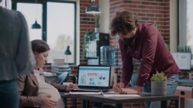 Hamile kadın iş projesi için iş arkadaşıyla takım çalışması yapıyor..