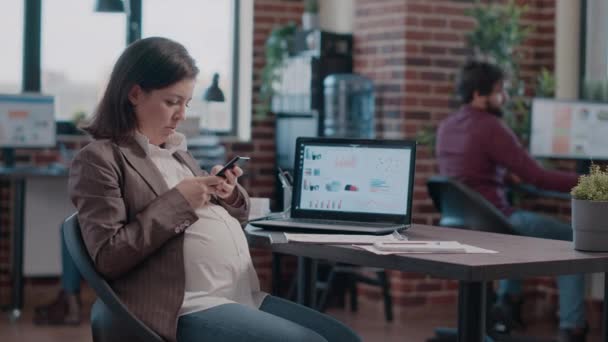 Gravid anställd skriva på smartphone skärm, arbetar på företag — Stockvideo