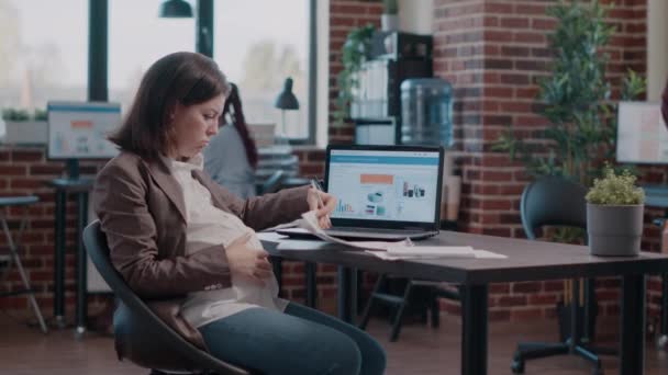 Gravid entreprenör som använder bärbar dator och papper för att utforma affärsprojekt — Stockvideo