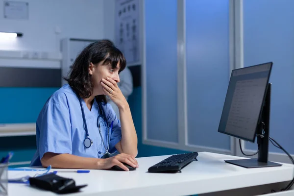 Infirmière fatiguée utilisant un ordinateur sur le bureau pendant qu'elle s'endort — Photo