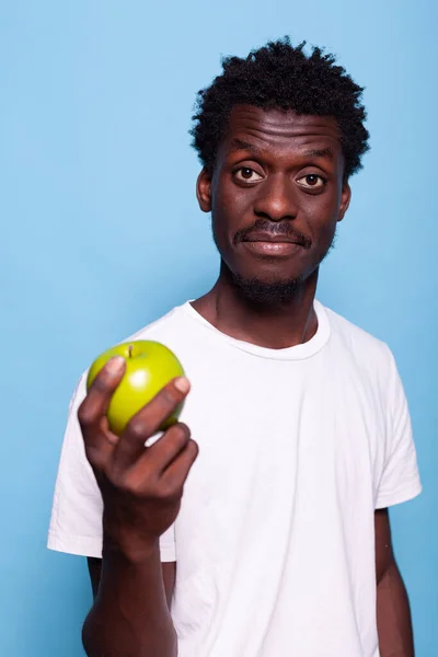 Retrato del hombre sosteniendo manzana verde en la mano y mirando a la cámara — Foto de Stock