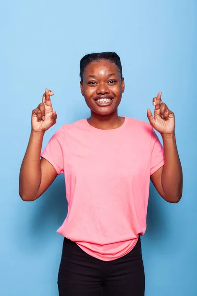 Retrato de estudante afro-americano sorridente com os dedos cruzados fazendo símbolo de desejo — Fotografia de Stock