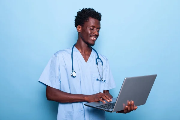 Assistente médico afro-americano olhando para laptop na mão — Fotografia de Stock