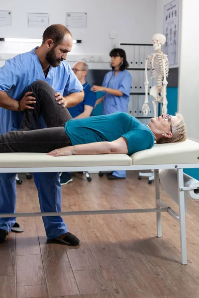 Chiropraticien essayant de soulager la pression du genou du patient — Photo