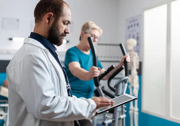 Patiente âgée utilisant un vélo stationnaire pour la récupération physique — Photo