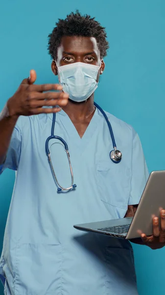 顔マスクをつけてノートパソコンを持ってる看護師 — ストック写真