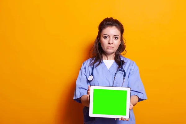 Assistente medico che mostra tablet digitale con schermo verde orizzontale — Foto Stock