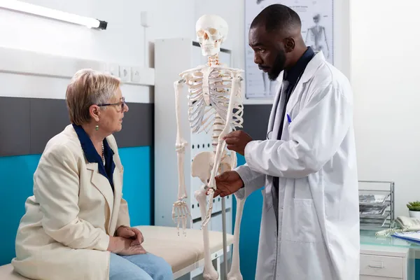Specialistterapeut läkare som håller anatomiska mänskliga skelett arm förklara ben smärta — Stockfoto