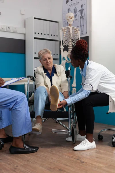 Minder valide oudere vrouw die een knieonderzoek doet tijdens een fysiotherapie afspraak — Stockfoto