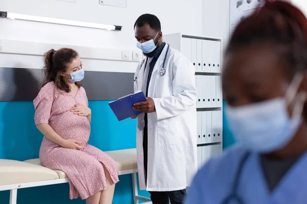 Médico mostrando papéis de check-up para mulher grávida — Fotografia de Stock