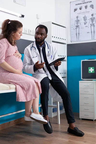 Médecin montrant un appareil numérique avec diagnostic à la patiente enceinte — Photo
