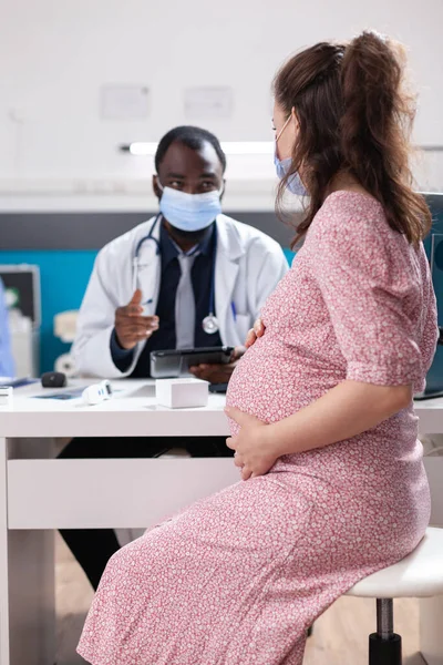 Médico fazendo consulta médica com mulher grávida — Fotografia de Stock