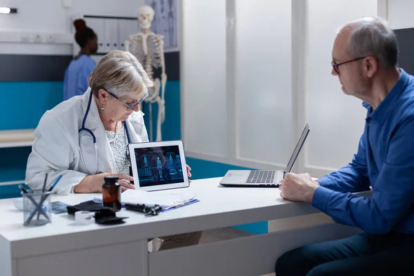 Медик і пацієнт аналізують ілюстрації людського тіла на цифровому планшеті — стокове фото